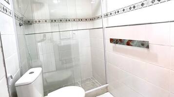 Ein kleines, modernes Badezimmer mit Duschkabine aus Glas, Toilette und Waschbecken.