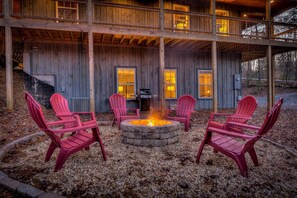 Eine Holzhütte mit einem Steinkamin und roten Adirondack-Stühlen.