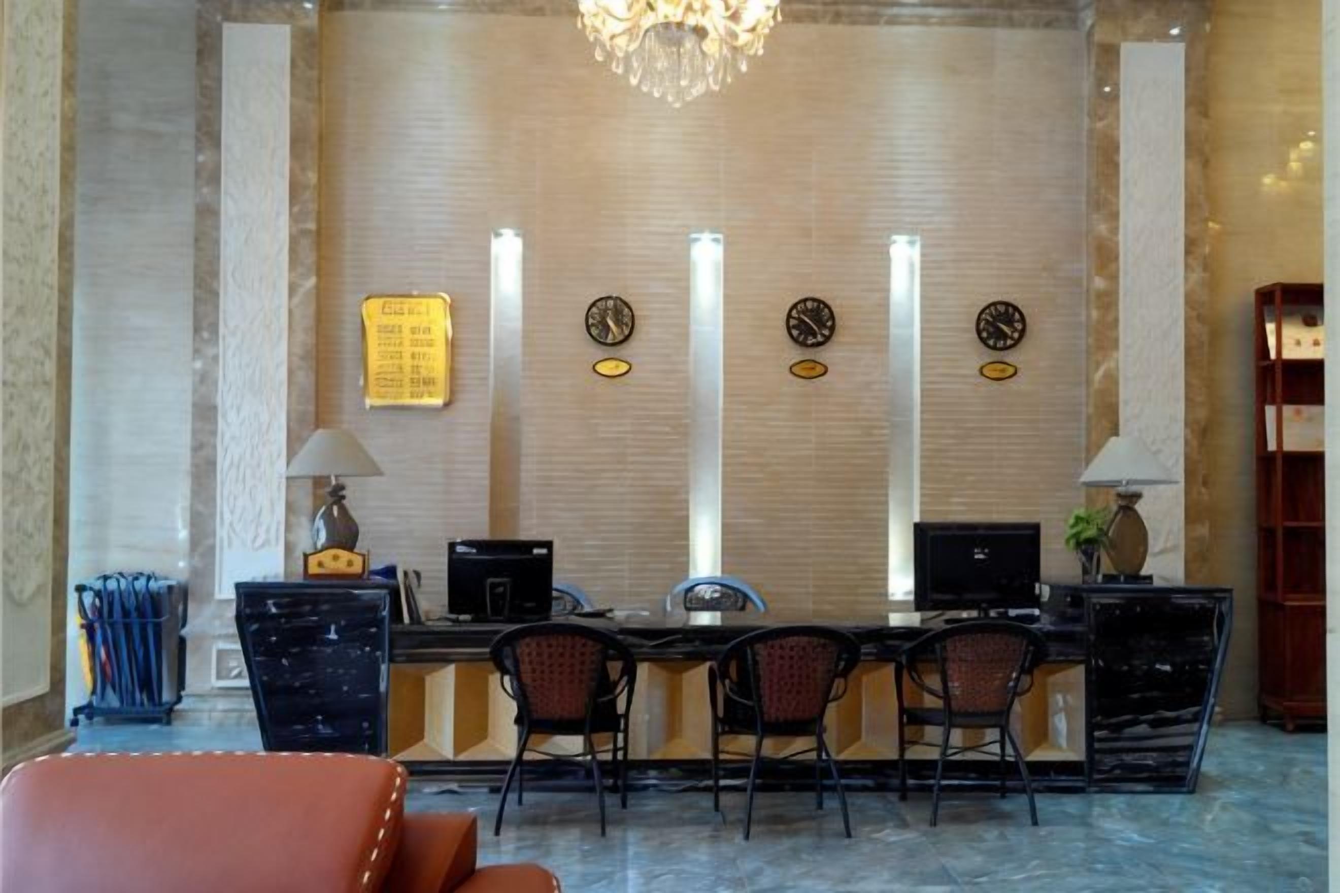 A reception desk with a computer, two chairs, a lamp, and a clock on the wall.