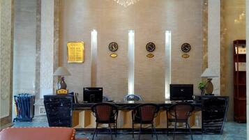 A reception desk with a computer, two chairs, a lamp, and a clock on the wall.