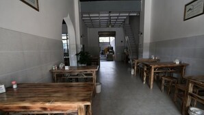 Un pasillo con mesas y sillas de madera, una escalera y vista a otra habitación.