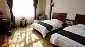 Una habitación de hotel con dos camas, una silla, una mesita y una lámpara.