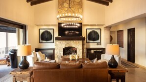 A spacious living room with a stone fireplace, leather sofas, and a chandelier. - Casa Vista Tranquila  (Cabo San Lucas)