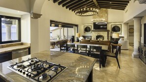 A spacious kitchen with a granite island, a dining area with a large table and chairs, and a fireplace. - Casa Vista Tranquila  (Cabo San Lucas)