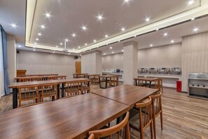 Un salón de conferencias con varias mesas y sillas, un proyector y una zona de bufé.