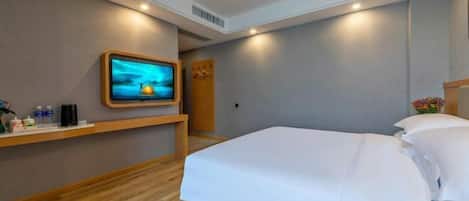 A hotel room with a bed, a TV mounted on the wall, a wooden nightstand, and a small table with toiletries.