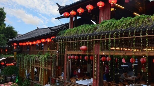 A traditional Chinese building with red lanterns, wooden balconies, and greenery. - Kaise Hotel (Lijiang Bailong Square Branch) (Lijiang)