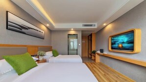 A modern hotel room with two beds, a wooden headboard, a flat-screen TV, and a painting on the wall. - Kaise Hotel (Lijiang Bailong Square Branch) (Lijiang)