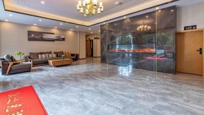A modern lobby with a marble floor, a sofa set, a chandelier, and a glass wall with a view. - Kaise Hotel (Lijiang Bailong Square Branch) (Lijiang)