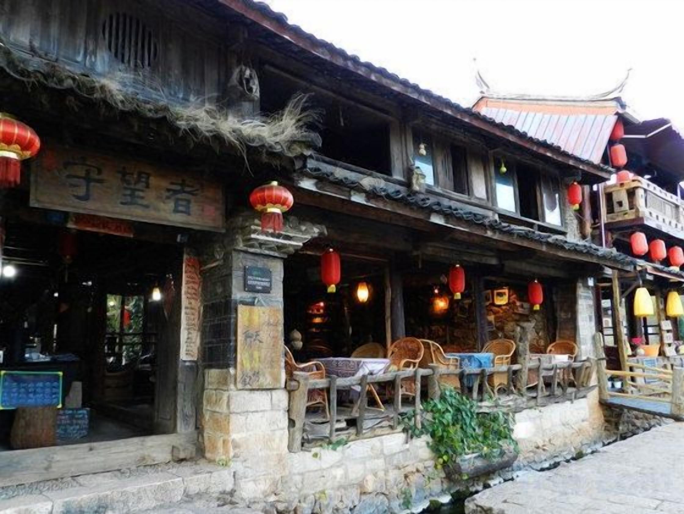 A traditional building with a tiled roof, wooden balcony, and red lanterns.