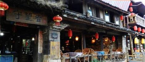 A traditional building with a tiled roof, wooden balcony, and red lanterns.