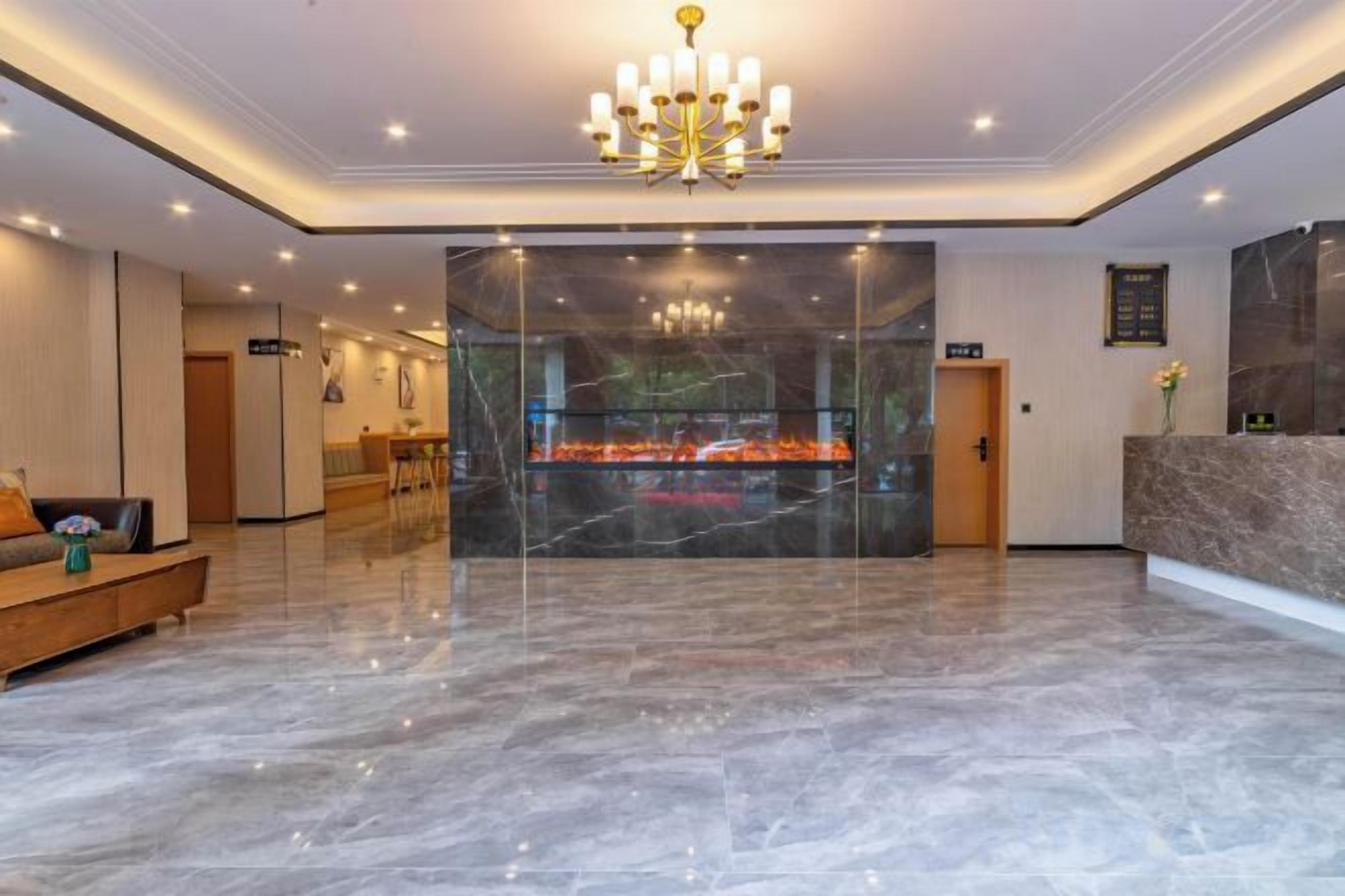 Un vestíbulo de hotel con piso de mármol, una recepción, una araña y una zona de estar.