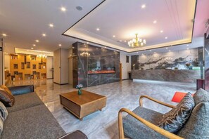 En modern hotellobby med en receptionsdisk, en sittgrupp och en vägg av marmor.