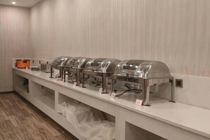 Ein Buffet mit mehreren Selbstbedienungsstationen, einer langen Theke und einem Holzboden.