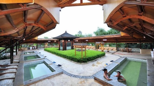 Uma área de spa com várias piscinas, passarelas de madeira e um gazebo.