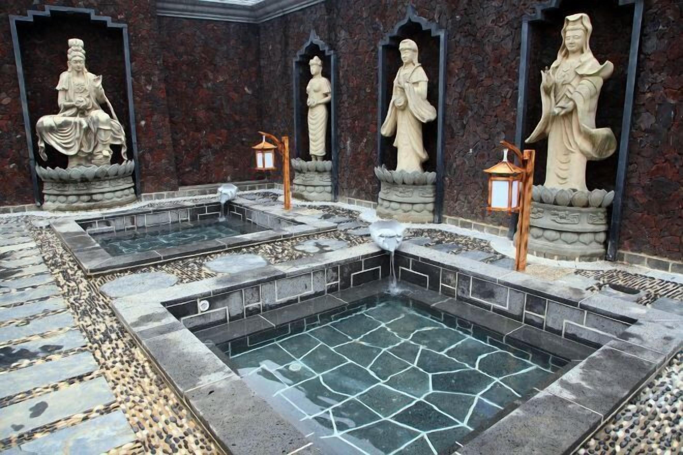 Un espace intérieur paisible agrémenté d’une fontaine et de statues, ainsi que de lanternes.