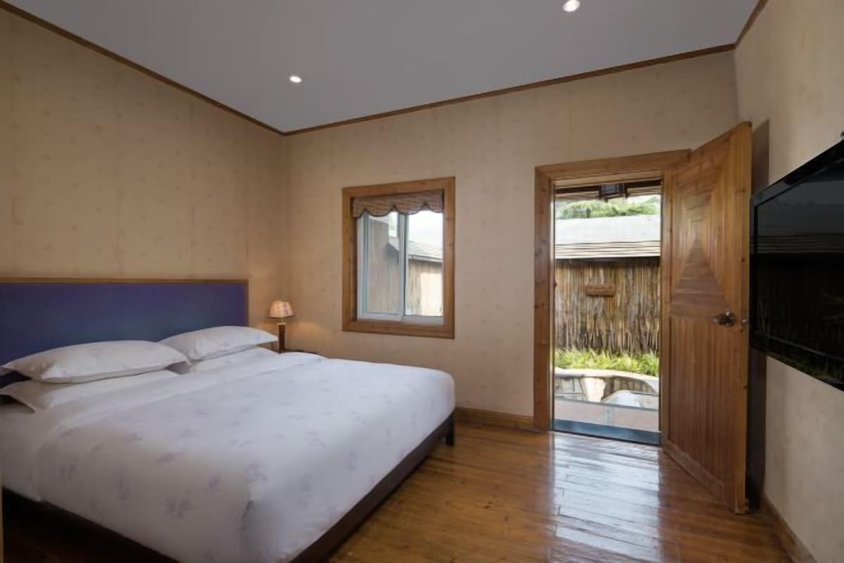 Quarto com cama, janela e porta que dá para área externa.