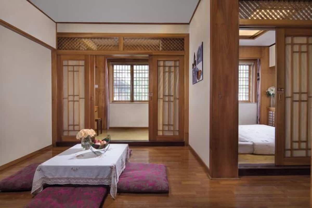 A traditional Japanese room with tatami flooring, a low table with a vase, and sliding doors.