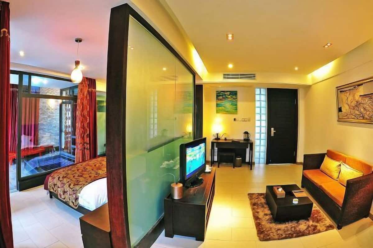 A modern hotel room with a bed, a TV, a sofa, and a dining area.