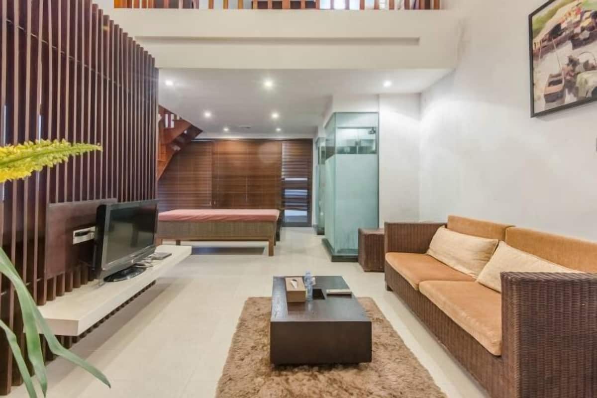 A modern living room with a sofa, a TV, a coffee table, and a staircase leading to an upper level.