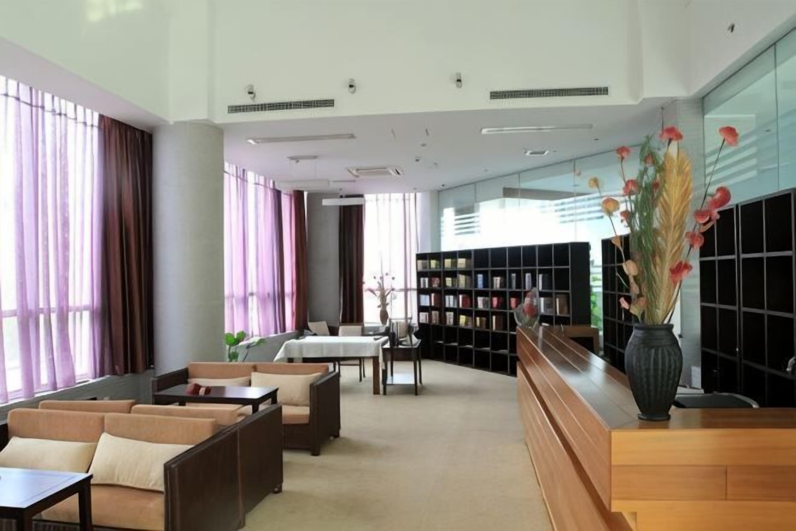 A spacious lobby with seating, a reception desk, and a bookshelf.