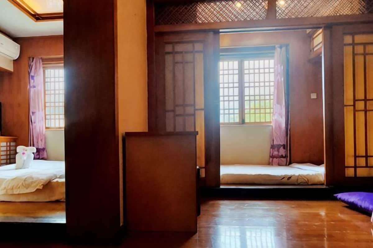A traditional Japanese-style room with tatami flooring, sliding doors, and a low wooden bed.