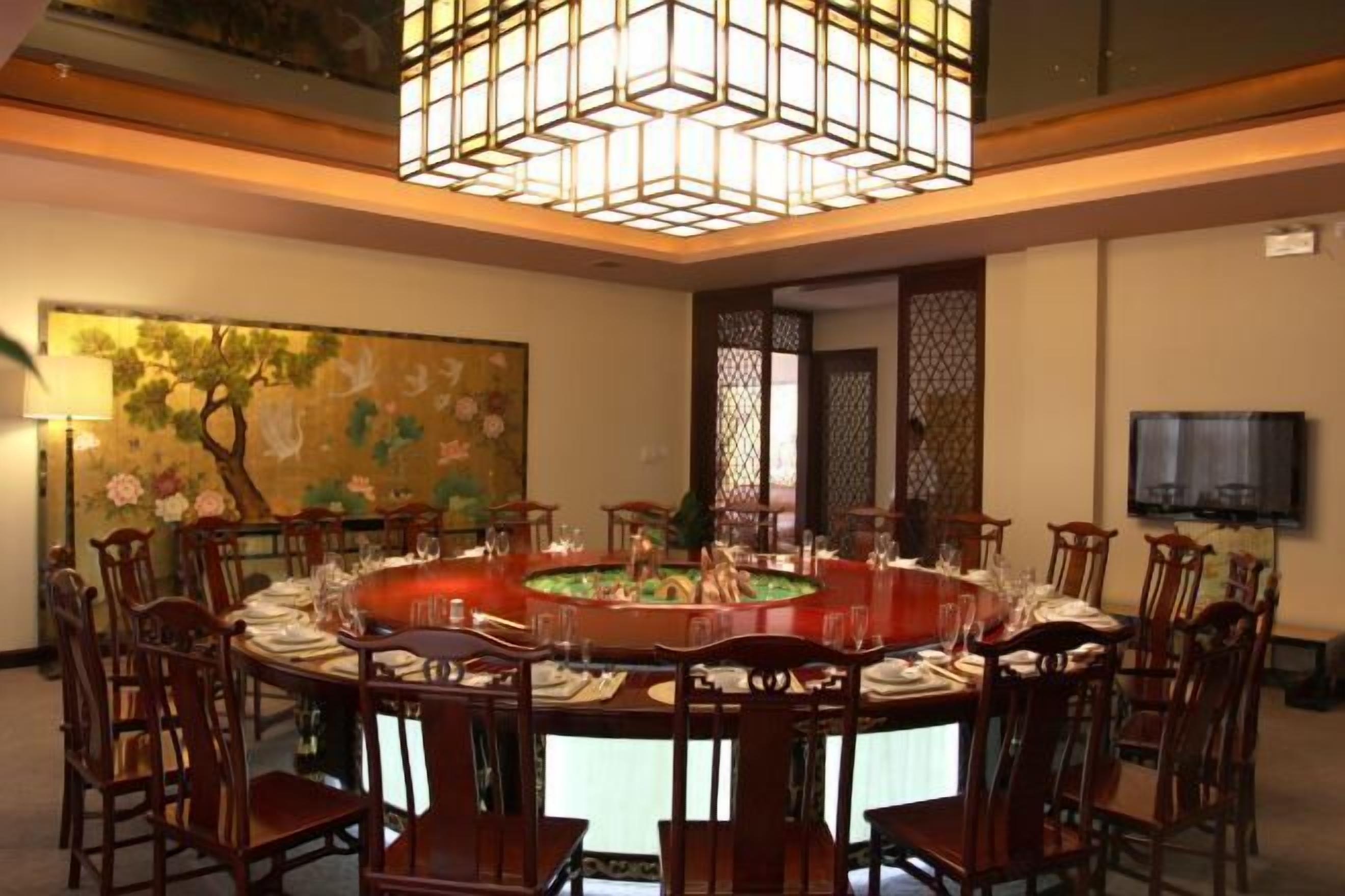 A dining area with a round table set for eight, surrounded by wooden chairs.