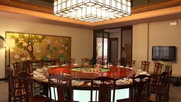 A dining area with a round table set for eight, surrounded by wooden chairs.