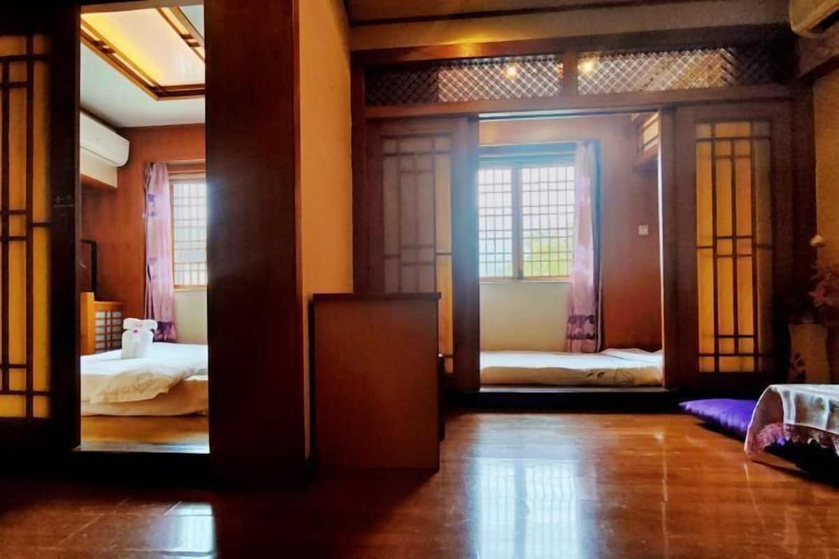 A traditional Japanese-style room with tatami flooring, sliding doors, and a bed with a white bedding set.