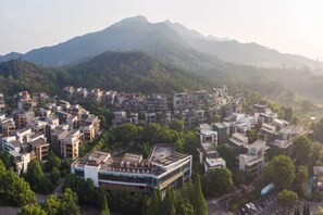 A residential area with modern buildings, surrounded by greenery and mountains.
