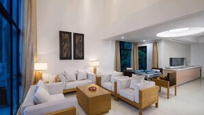 Quarto de hotel moderno com área de estar, mesa de jantar e cozinha.