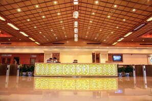 A hotel lobby with a reception desk, a television, and a ceiling with a grid pattern.
