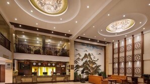 Um hall amplo com uma mesa de recepção, área de estar e um mural de montanhas.