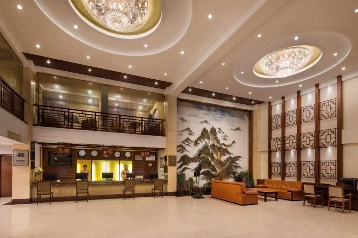 A spacious lobby with a reception desk, seating area, and a mural of mountains.