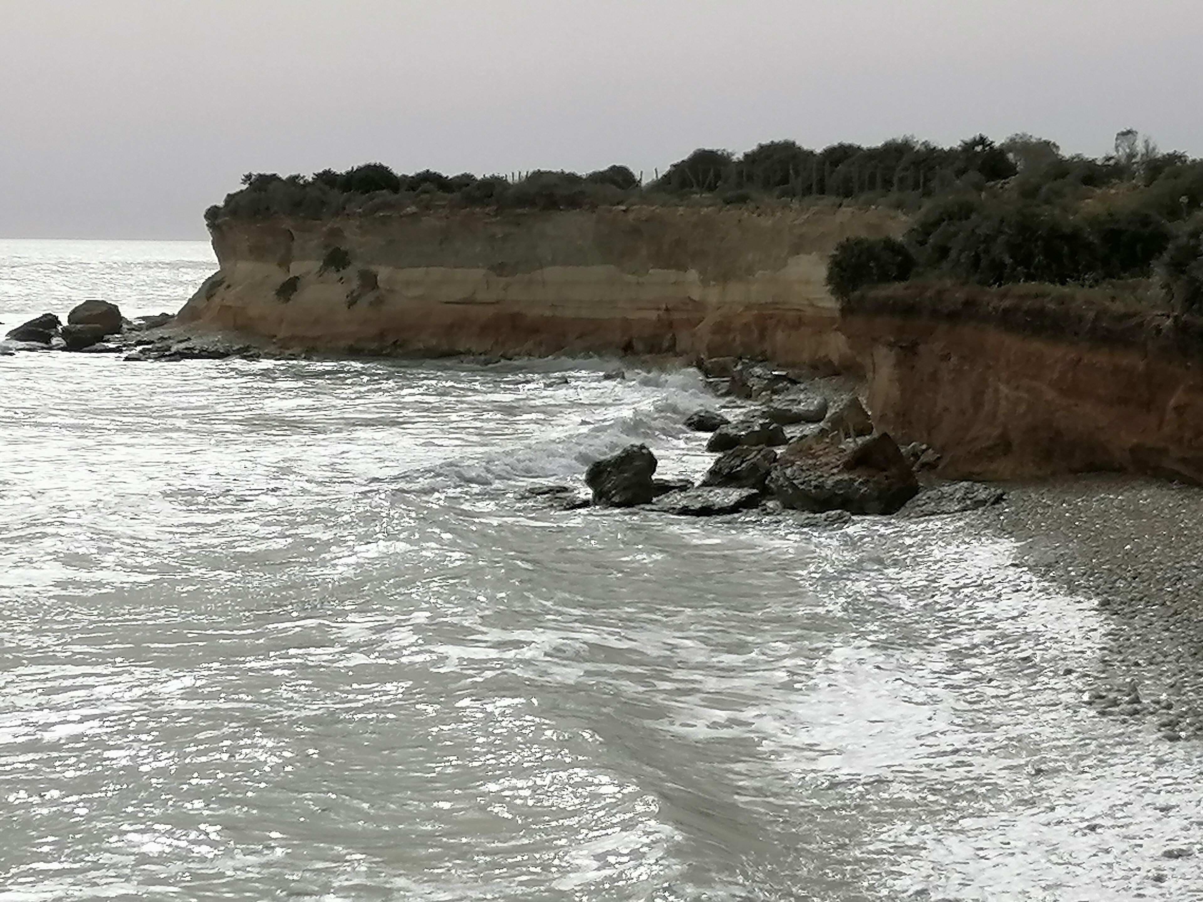 A coastal landscape with a rocky shoreline and cliffs.