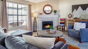 Un salon avec une cheminée, deux canapés, une table basse et un tapis.
