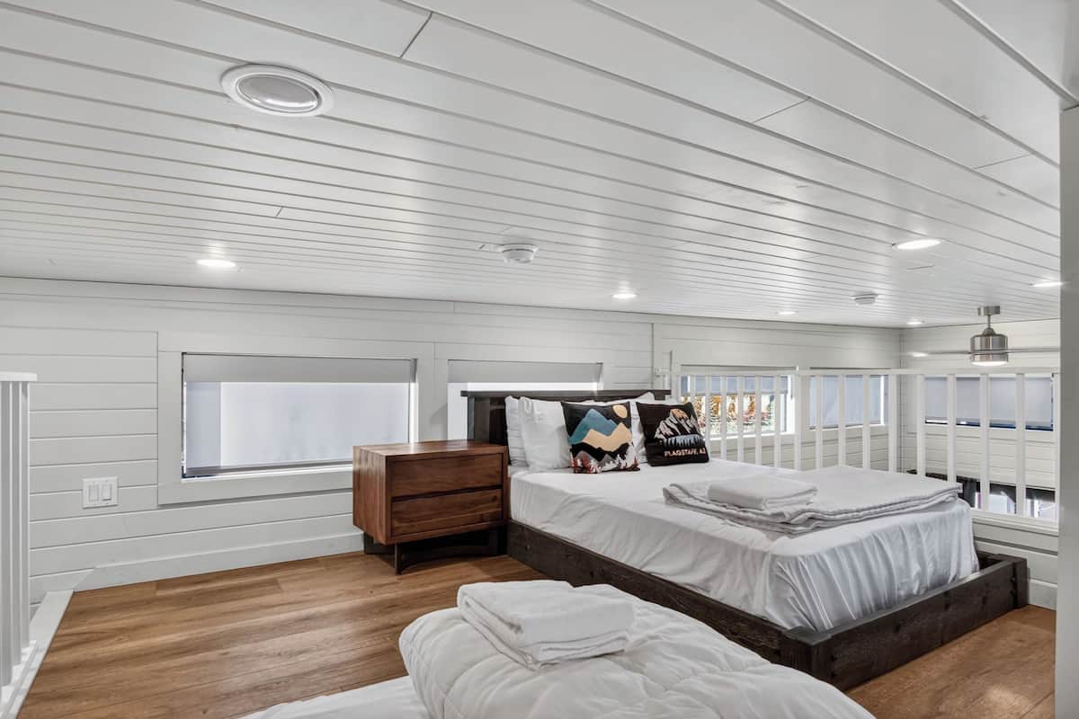 Une chambre à coucher avec un grand lit, une table de chevet, une fenêtre et un plafond doté d’un éclairage encastré.