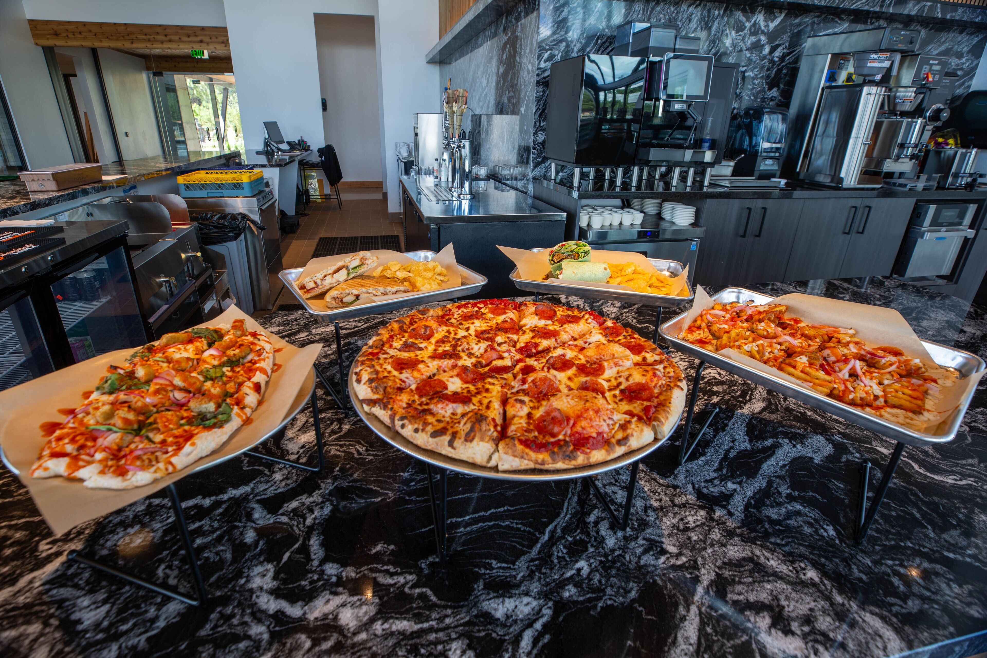 A buffet area with various pizzas and a coffee station.