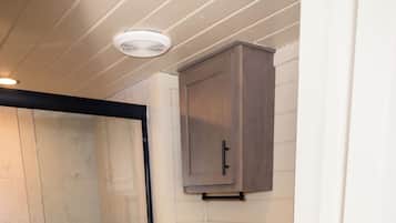 Une salle de bain avec douche, toilettes et meuble de rangement.