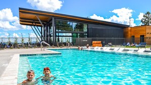 A modern pool area with clear blue water, a wooden deck, and lounge chairs.