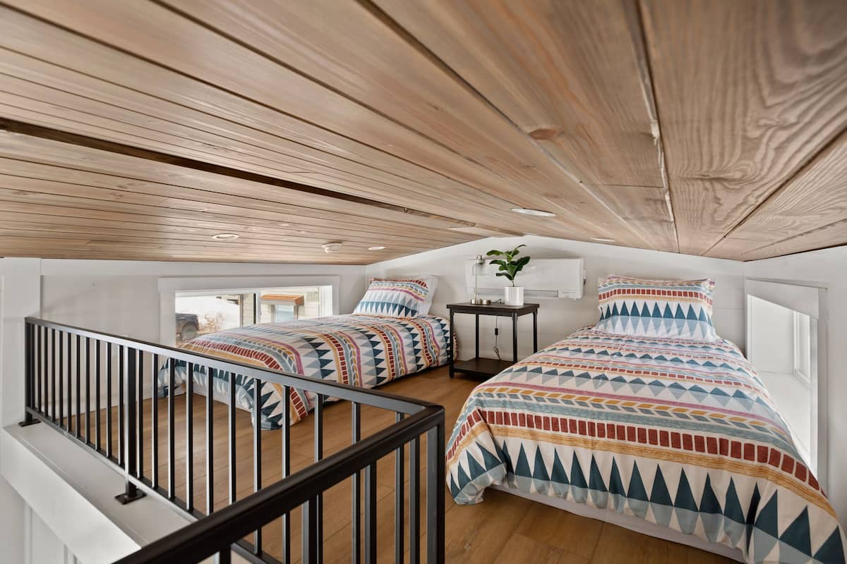 Une chambre avec deux lits, un plafond en bois et une petite table sur laquelle est posée une plante.