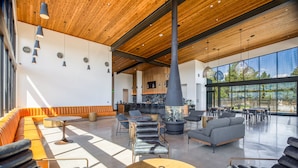 A spacious lobby with a wooden ceiling, modern seating, a bar area, and large windows offering a view of the outdoors.