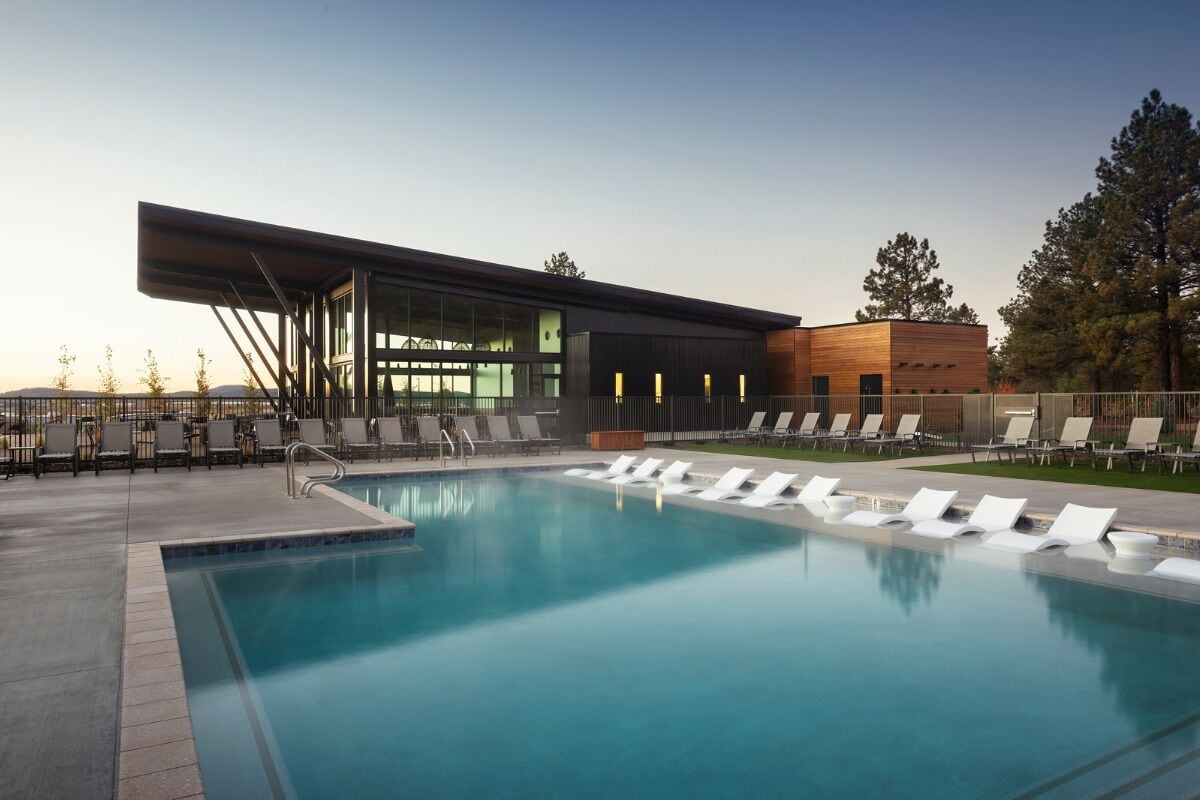 A modern pool area with lounge chairs and a building with large windows.