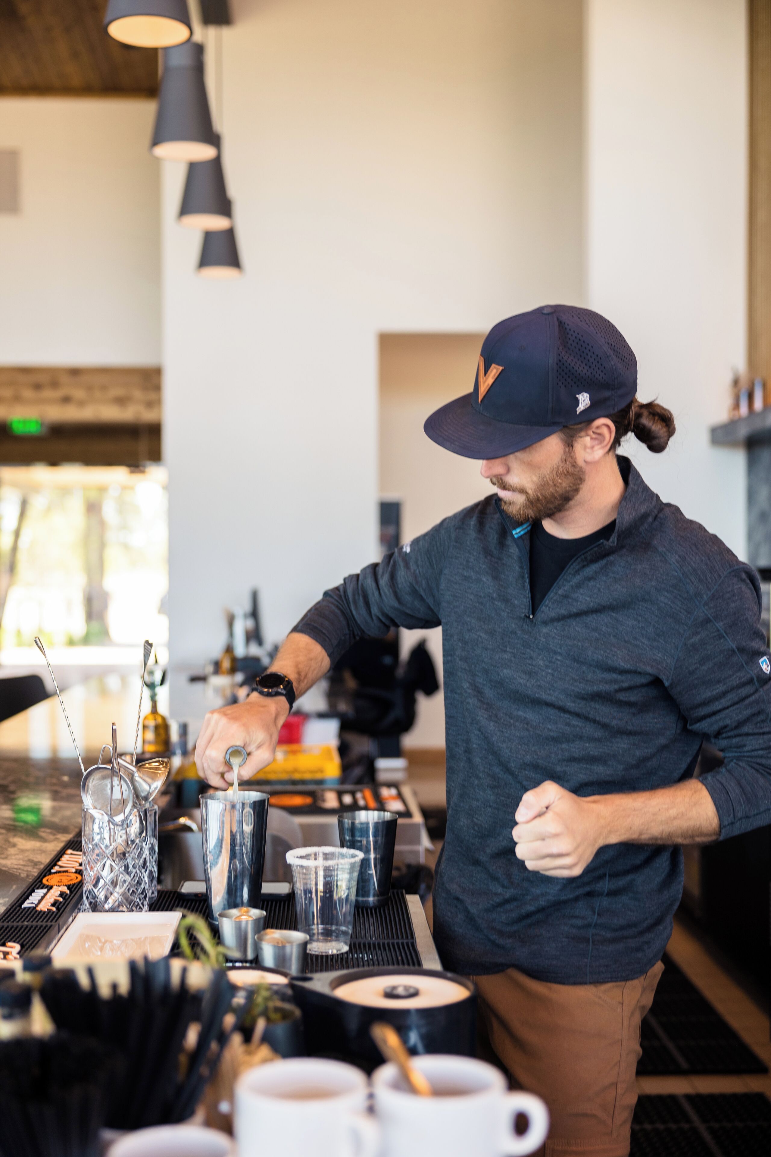 Une personne prépare des boissons au bar, en utilisant différents types de verres et de bouteilles.