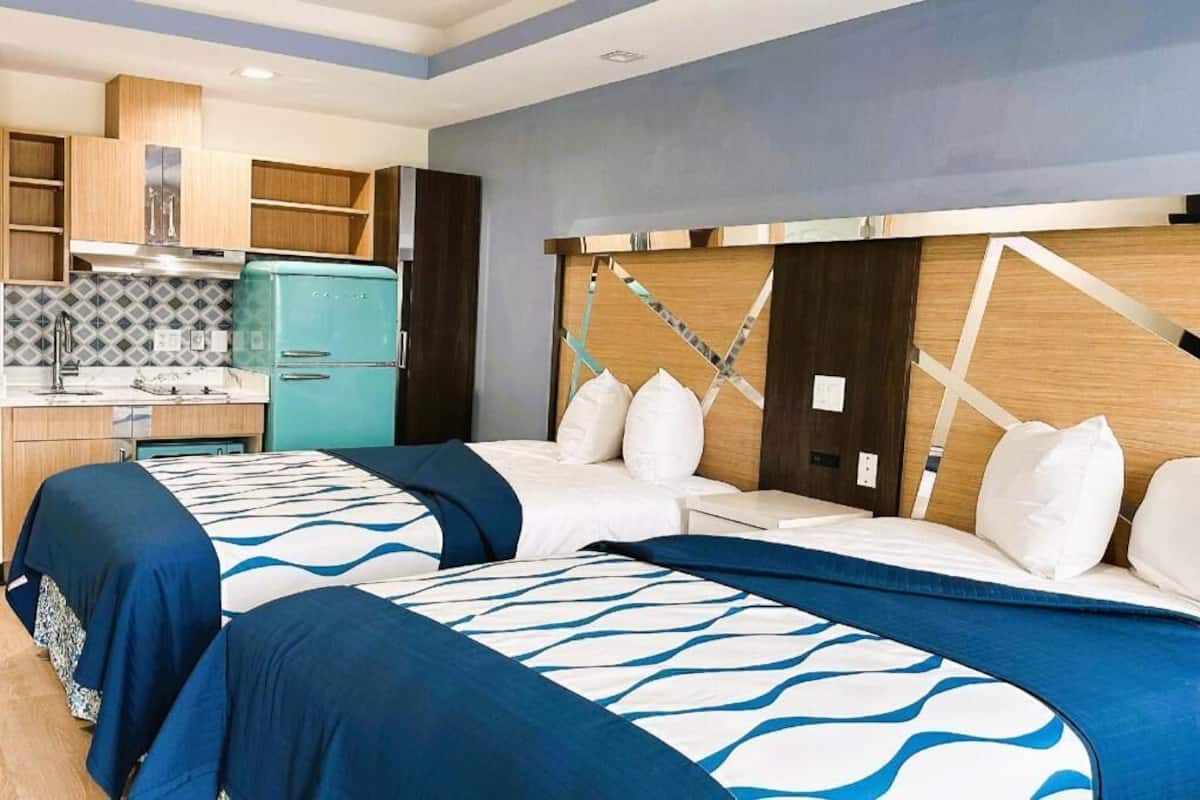 Una camera d'albergo con due letti, angolo cottura e design moderno.