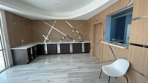 A modern kitchen with a curved ceiling, wooden paneling, and a marble floor.