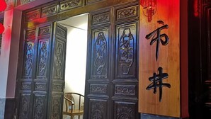 Uma porta de madeira tradicional com esculturas detalhadas e caracteres chineses.