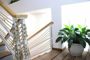 A staircase with a white handrail and a potted plant on the landing. - Shijing Homestay (Jianshui Ancient City Branch) (Jianshui)