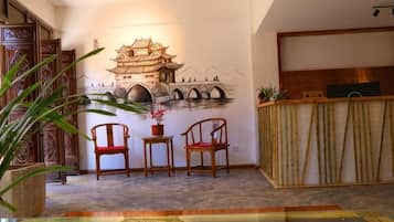 Quarto com mural de arquitetura chinesa tradicional, mobiliário de madeira e mesa de vidro.