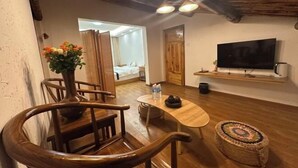 Een gezellige kamer met een houten trap, een kleine tafel met een bloevas, een televisie en een bed op de achtergrond.